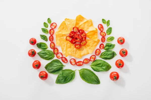 Vista dall'alto di nachos, peperoncini tagliati, foglie di basilico e pomodorini maturi — Foto stock