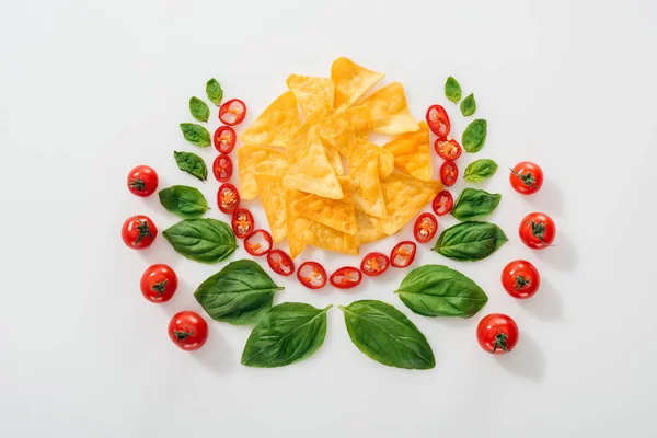 Flache Lage mit Nachos, geschnittenen Chilischoten, Basilikumblättern und reifen Kirschtomaten — Stockfoto