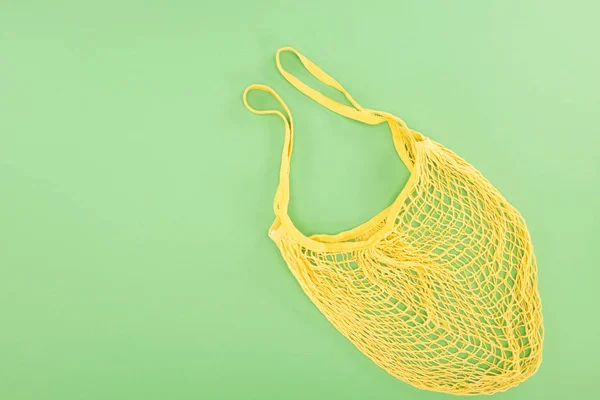 Vista superior de la bolsa de hilo amarillo sobre fondo verde claro - foto de stock