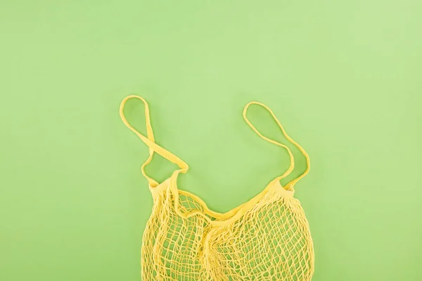 Vista superior de la bolsa de hilo vacía amarilla sobre fondo verde claro - foto de stock