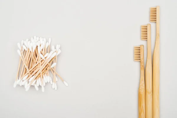 Vista dall'alto di spazzolini di bambù e tamponi di cotone su sfondo grigio — Foto stock