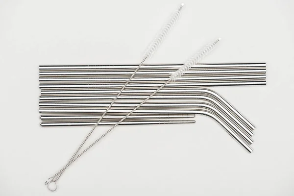 Top view of stainless steel straws and cleaning brushes isolated on grey — Stock Photo