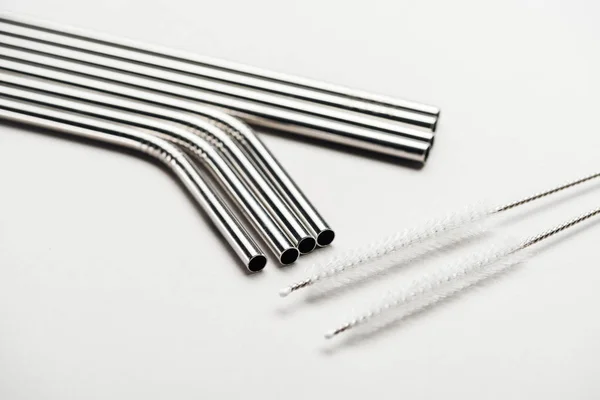 Close up view of of stainless steel straws and cleaning brushes on grey — Stock Photo