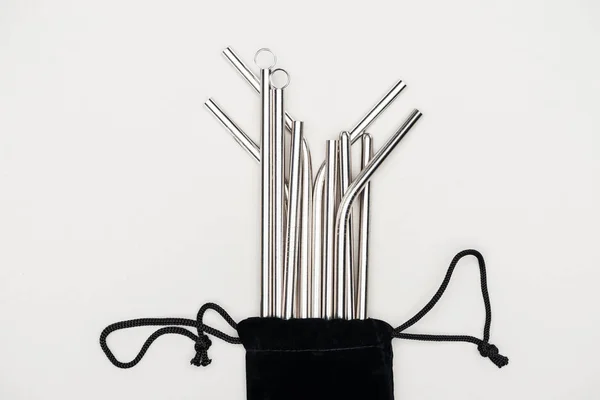 Вид зверху на соломинки з нержавіючої сталі в чорному мішку ізольовані на сірому — стокове фото