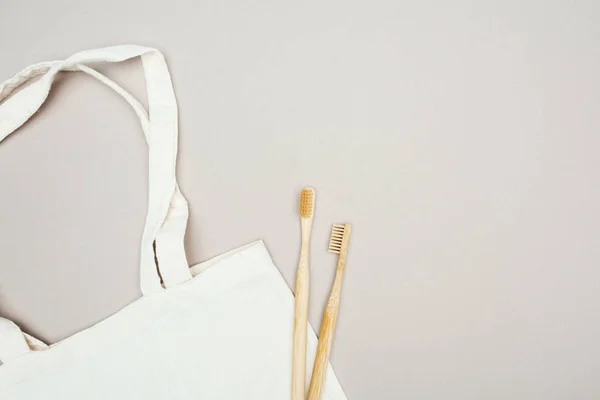 Cepillos de dientes de madera y bolsa de algodón blanco sobre fondo gris - foto de stock