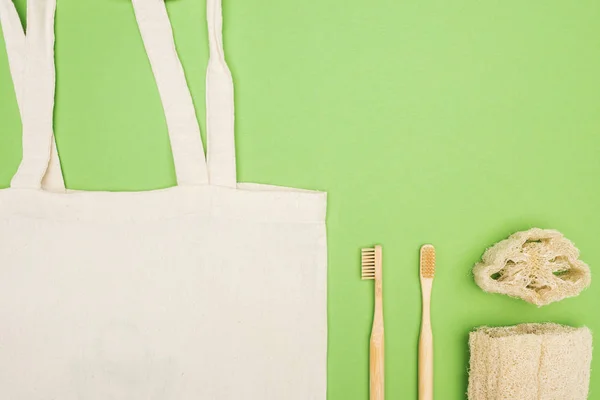 Cepillos de dientes de bambú orgánicos, esponja y bolsa de algodón sobre fondo verde claro - foto de stock