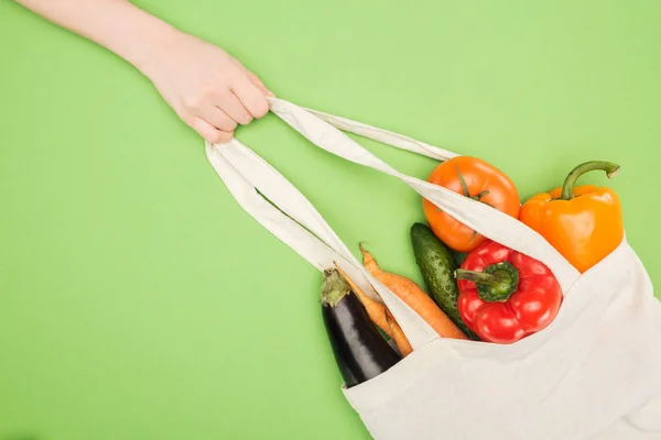 Vista parziale della donna che tiene in mano la maniglia del sacchetto di cotone pieno di verdure mature — Foto stock