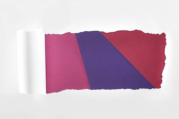Papel branco texturizado esfarrapado com borda rolada sobre fundo colorido — Fotografia de Stock