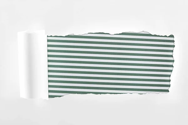 Papier blanc texturé déchiqueté avec bord roulé sur fond rayé vert — Photo de stock