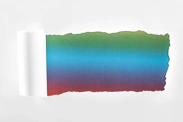 Rasgado papel branco com borda rolada sobre fundo multicolorido — Fotografia de Stock