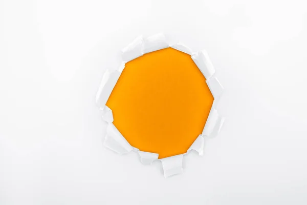 Buraco irregular em papel branco texturizado sobre fundo laranja — Fotografia de Stock
