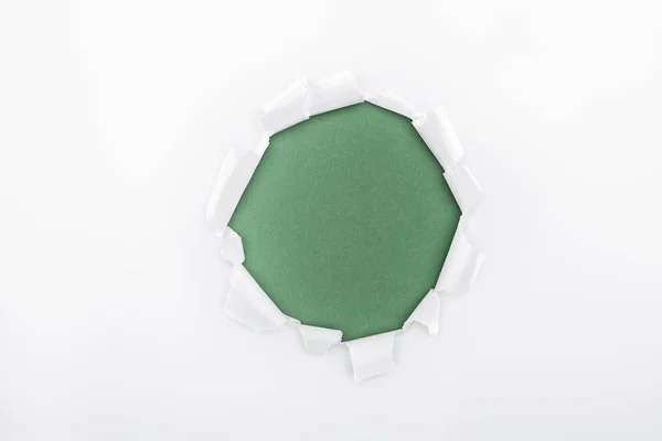 Ragged hole in textured white paper on green background — Stock Photo