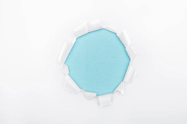 Buraco rasgado em papel branco texturizado sobre fundo azul claro — Fotografia de Stock