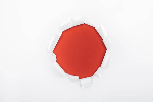 Agujero rasgado en papel blanco texturizado sobre fondo rojo - foto de stock