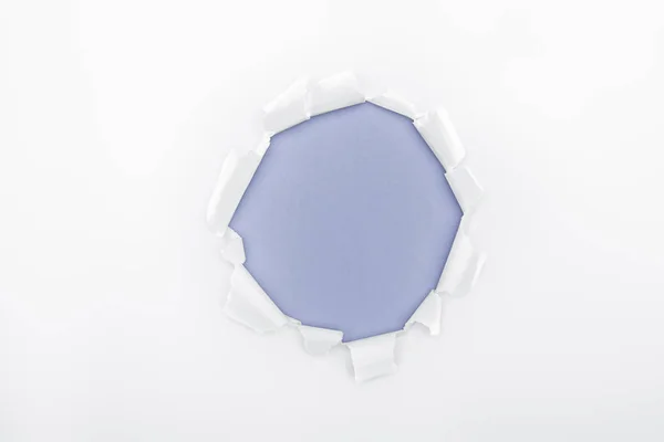 Ripped hole in white textured paper on blue background — Stock Photo