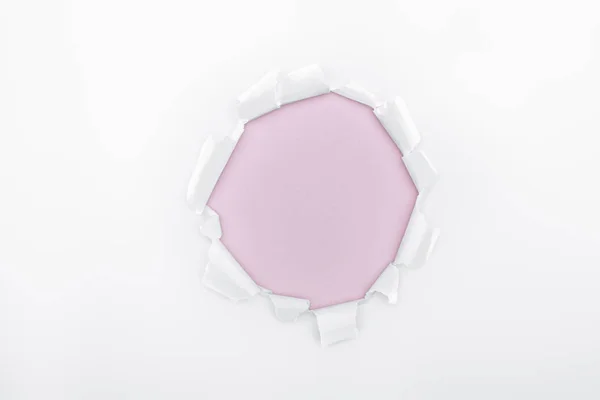 Ripped hole in white textured paper on pink background — Stock Photo