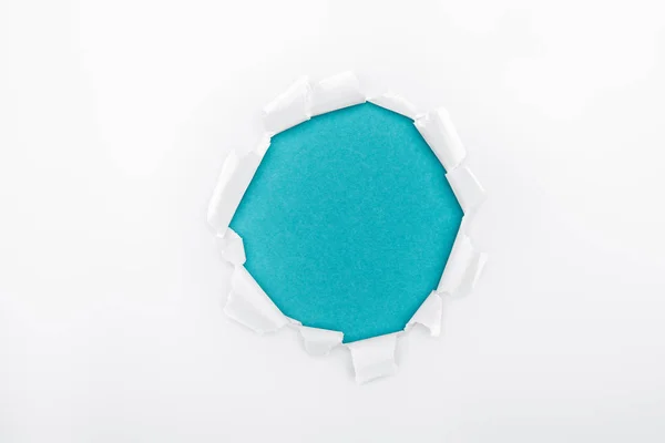 Рваная дыра в белой текстурированной бумаге на синем фоне — стоковое фото