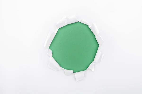 Torn hole in white textured paper on green background — Stock Photo