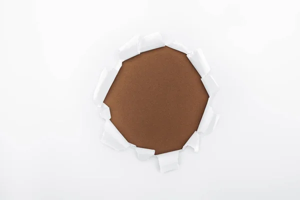 Agujero roto en papel blanco texturizado sobre fondo marrón - foto de stock