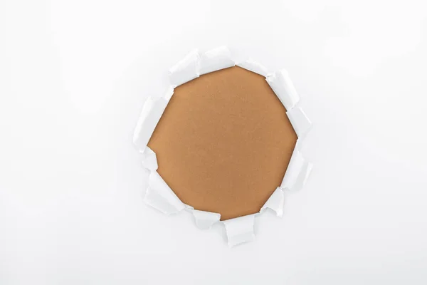Agujero rasgado en papel texturizado blanco sobre fondo marrón - foto de stock