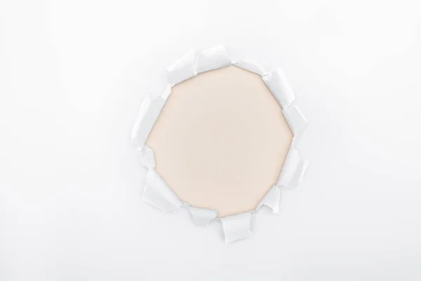 Ripped hole in white textured paper on ivory background — Stock Photo