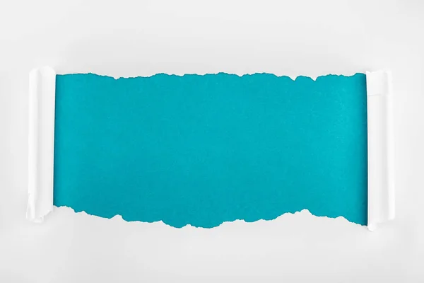 Papel texturizado blanco rasgado con bordes rizados sobre fondo azul - foto de stock
