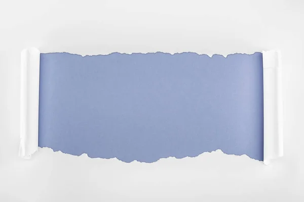 Papier blanc déchiré avec bords roulés sur fond bleu — Photo de stock