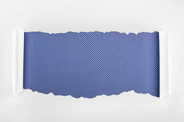 Papel texturizado blanco rasgado con bordes rizados sobre fondo punteado púrpura - foto de stock