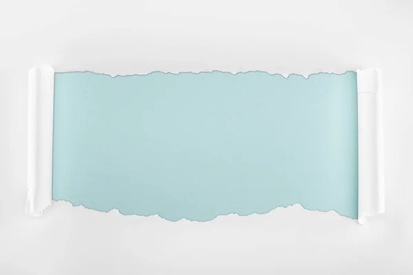 Papier texturé blanc éclaté avec bords bouclés sur fond bleu clair — Photo de stock