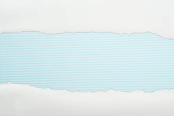 Papier texturé blanc déchiqueté avec espace de copie sur fond rayé bleu clair — Photo de stock