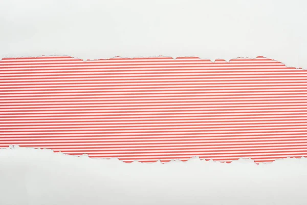 Ripped white textured paper with copy space on red striped background — Stock Photo