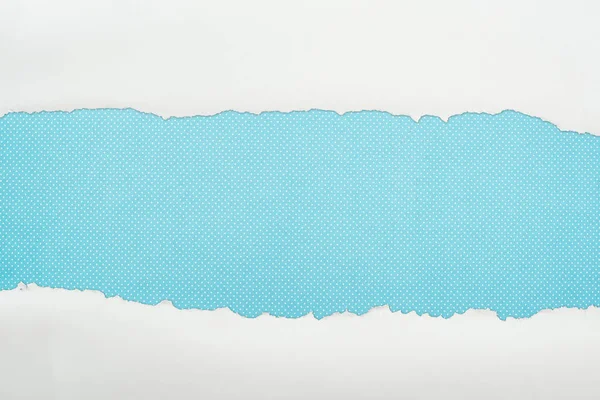 Papel texturizado blanco rasgado con espacio de copia sobre fondo de lunares azul - foto de stock