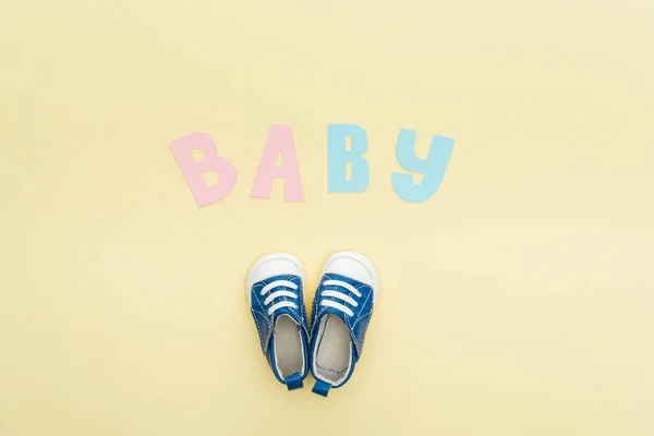 Top view of sneakers and baby lettering isolated on yellow — Stock Photo