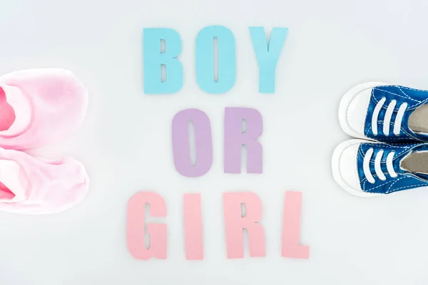 Top view of booties and sneakers, boy or girl lettering isolated on white — Stock Photo