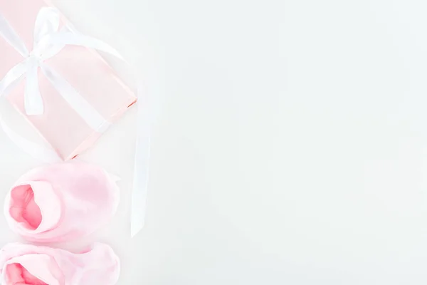 Вид зверху рожеві пінетки та подарункова коробка на білому тлі з місцем для тексту — стокове фото
