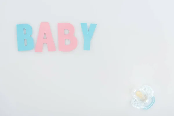 Top view of pacifier and pink and blue baby lettering isolated on white with copy space — Stock Photo