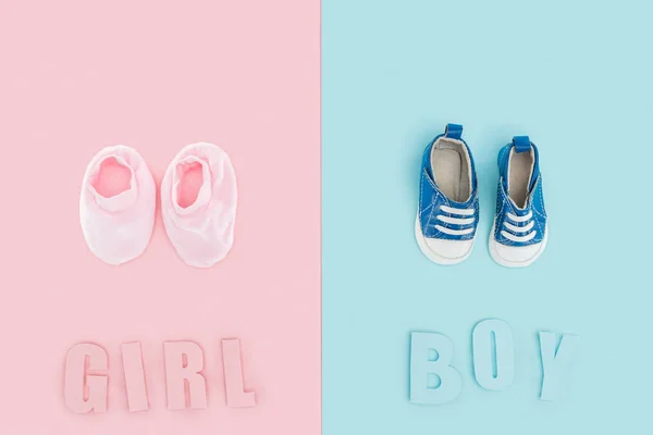 Vista superior de letras de niño y niña y zapatillas de deporte, botines sobre fondo rosa y azul - foto de stock