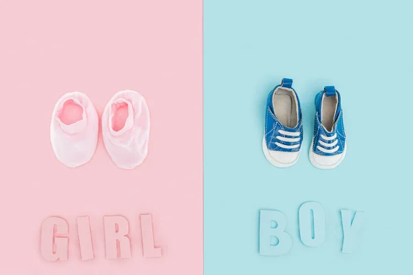 Top view of boy and girl lettering and sneakers, booties on pink and blue background — Stock Photo