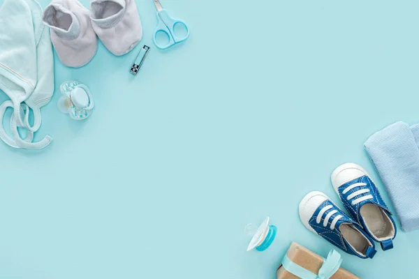 Вид сверху на ножницы, соски, подарок, кроссовки, капот, ботинки, шляпу на голубом фоне — стоковое фото