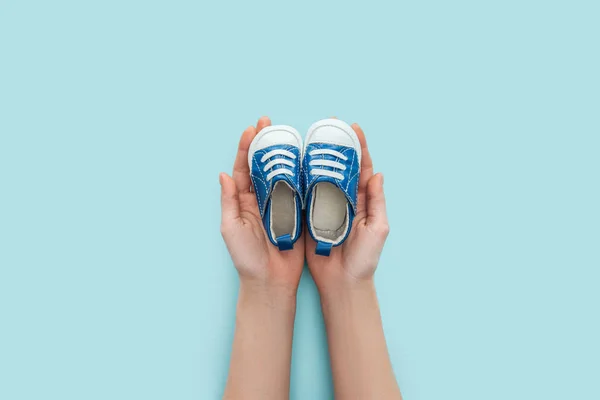 Partial view of adult man holding sneakers on blue background with copy space — Stock Photo