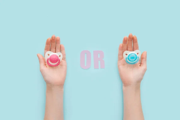 Partial view of women holding pacifiers with or lettering — Stock Photo