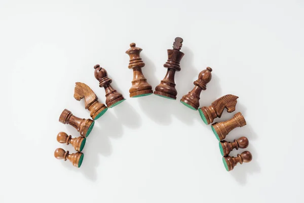 Top view of semicircle made of brown wooden chess figures on white background — Stock Photo