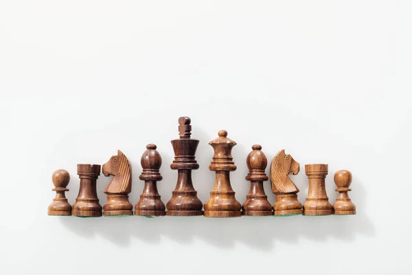 Top view of row made of brown wooden chess figures on white background — Stock Photo