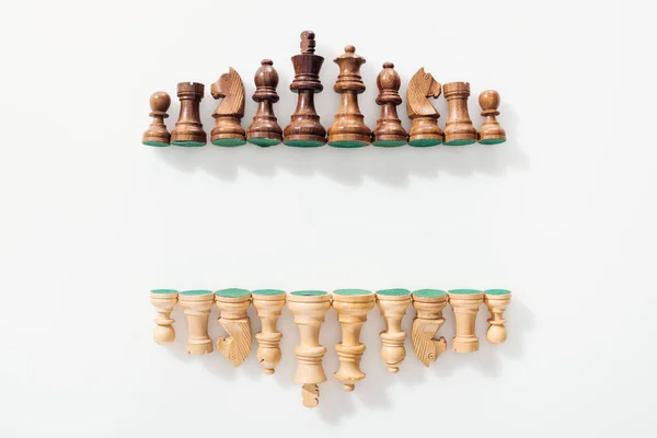 Top view of rows made of brown and beige wooden chess figures on white background with copy space — Stock Photo
