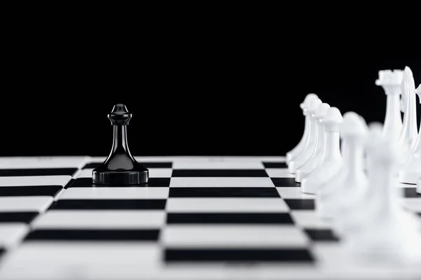 Enfoque selectivo de tablero de ajedrez con figuras de ajedrez blanco y peón negro en frente aislado en negro - foto de stock