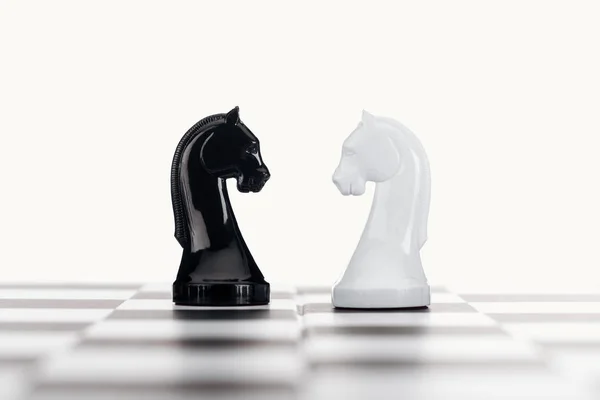 Selective focus of chessboard and white and black knights isolated on white — Stock Photo