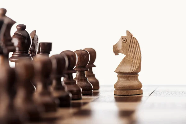 Селективный фокус деревянной шахматной доски с шахматными фигурами и рыцарем спереди, изолированным на белом — стоковое фото