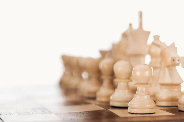 Enfoque selectivo de tablero de ajedrez de madera beige y marrón con figuras de ajedrez aisladas en blanco - foto de stock