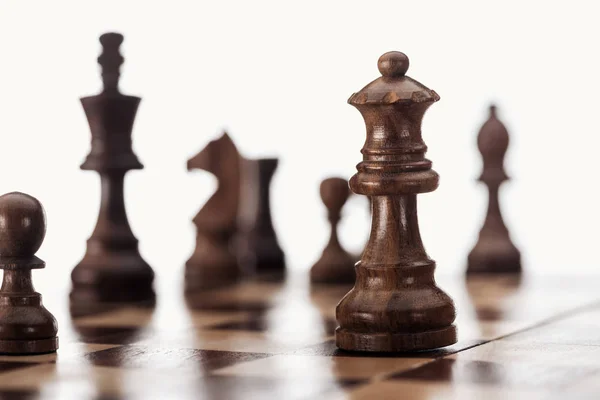 Enfoque selectivo de tablero de ajedrez de madera con figuras de ajedrez de color marrón oscuro aisladas en blanco - foto de stock