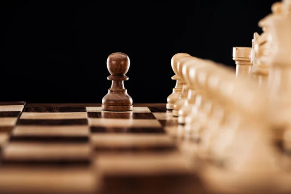 Selective focus of wooden chessboard with chess figures and pawn in front isolated on black — Stock Photo